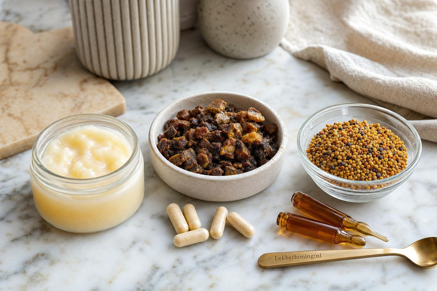 Vergelijking van royal jelly, propolis en bijenpollen op een marmeren werkblad met subtiele Lekkerhoning.nl branding.